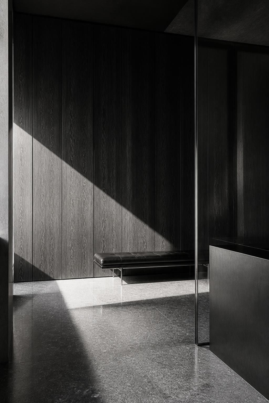 Recepção mínima em preto e branco, com painel de madeira escura, vidro e um banco solitário